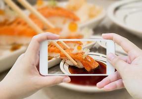 Fotografieren von gegrilltem Lachssushi in Essstäbchen foto