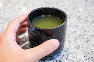 Frau Hand halten heiße grüne Teetasse foto