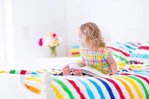kleines Mädchen liest ein Buch im Bett foto