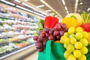 frisches obst und gemüse in wiederverwendbarer grüner einkaufstasche mit supermarkt-lebensmittelgeschäft verschwommener defokussierter hintergrund mit bokeh-licht foto