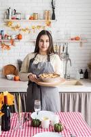 Porträt einer Frau, die Kürbiskuchen für Thanksgiving-Dinner in der heimischen Küche zubereitet foto