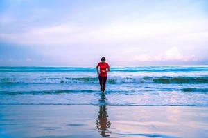 Mädchen, das morgens am Strand joggt. entspannen und glücklich mit dem Laufen auf dem Meer. im Sommer foto