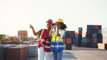 Vorarbeiterin oder Ingenieurin mit Fernglas und Partner, die auf den Problemschwerpunkt des Frachtcontainertanks beim Logistiktransport des Lagercontainers zeigen foto