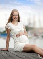 Schwangerschaftsfrau, die nahe Seehafen sitzt foto