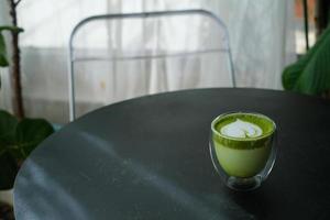 Colse heiße Matcha-Grüntee-Latte-Kunst in doppelwandigem Glas auf dem Tisch im Café. foto