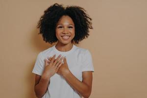 dankbare junge Afrikanerin isoliert auf gelbem Studiohintergrund, die Wertschätzung und Liebe zeigt foto