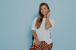 schöne brünette frau trägt weißes lässiges t-shirt und rock, die im studio aufwerfen foto