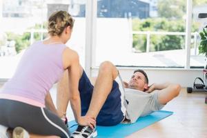 Trainer hilft fit Mann dabei zu sitzen