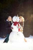 zwei junge Frauen umarmen Schneemann