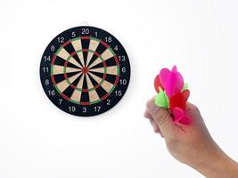 Die menschliche Hand wirft das Dartziel auf die Dartscheibe. Die Hand eines Mannes wirft einen Pfeil auf das Ziel foto