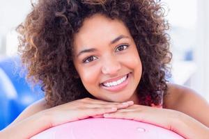 Porträt einer fit lächelnden jungen Frau mit Fitnessball foto