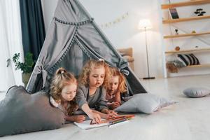 Zeichnen lernen. Mädchen legt sich im Zelt hin. Gruppe von Kindern ist tagsüber zusammen zu Hause foto