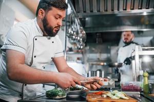 Zutaten gießen. professioneller koch, der essen in der küche zubereitet foto