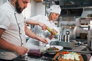 drei Leute. veganen salat zubereiten. professioneller koch, der essen in der küche zubereitet foto