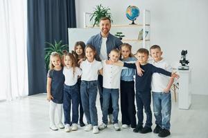 stehen und lächeln. gruppe von kinderschülern im unterricht in der schule mit lehrer foto