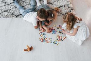 Puzzlespiel spielen. Gruppe von Kindern ist tagsüber zusammen zu Hause foto