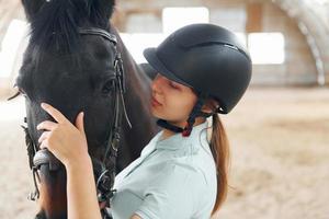 Nahaufnahme. eine junge frau in jockeykleidung bereitet sich auf einen ritt mit einem pferd auf einem stall vor foto