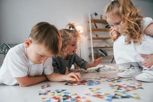 Puzzlespiel spielen. Gruppe von Kindern ist tagsüber zusammen zu Hause foto