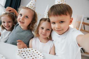 Selfies machen. Geburtstag feiern. Gruppe von Kindern ist tagsüber zusammen zu Hause foto