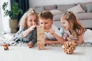 Holzturmspiel spielen. Gruppe von Kindern ist tagsüber zusammen zu Hause foto