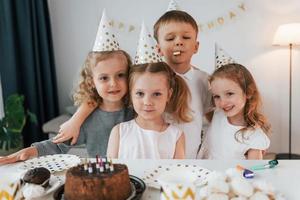 für die Kamera posieren. Geburtstag feiern. Gruppe von Kindern ist tagsüber zusammen zu Hause foto