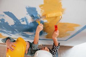 in Arbeit. Zwei Jungen streichen Wände im Wohnzimmer foto