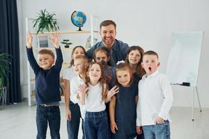 zusammen stehen. gruppe von kinderschülern im unterricht in der schule mit lehrer foto