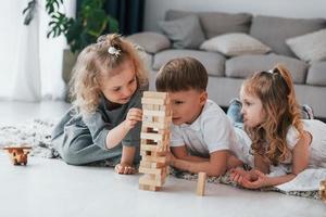 Holzturmspiel spielen. Gruppe von Kindern ist tagsüber zusammen zu Hause foto