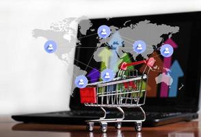 Erfolg beim Online-Shopping - Trolley und Laptop foto