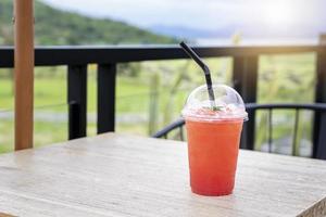 Erfrischungsgetränk für den Sommer, Eisbeerensaft in einem Plastikbecher mit verschwommenem grünem Hintergrund. organisch für ein gesundes, perfektes getränk für den sommer und kopierraum für text. Urlaub und gesundes Getränk foto