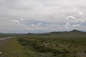 schöne mongolische Landschaft. Straße auf der linken Seite, mit nur einem Auto foto