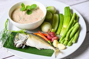 thailändische Makrelenküche, Makrelenfisch zum Kochen mit Chili, Schalotten, Knoblauch, grüne Auberginengurke, frisches Gemüse auf weißem Teller, Fischmehl foto