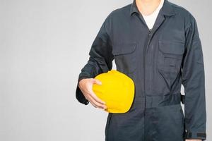 Nahaufnahme eines Arbeiters, der im blauen Overall mit Hardhat steht foto
