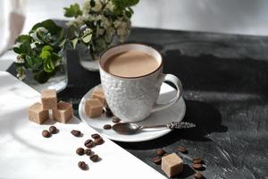 Flacher weißer Kaffee in einer Tasse. brauner Zucker und Kaffeebohnen foto