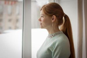 schöne frau mittleren alters, die zum fenster schaut. foto