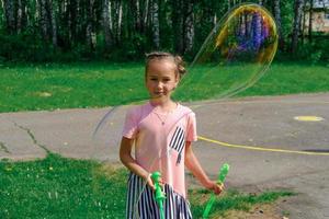 Mädchen, das draußen mit riesigen Seifenblasen spielt. foto