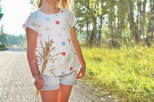 kleines Mädchen, das ein Bündel trockenes Gras hält. foto
