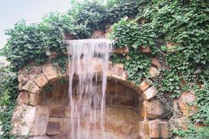 Wasserfall fließt und lebendige Pflanzendekoration im gemütlichen Stadtpark foto