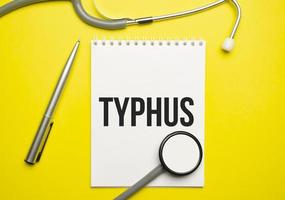 das Wort Typhus geschrieben auf einem weißen Notizblock auf gelbem Grund foto
