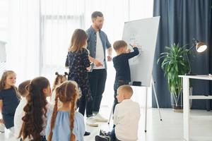 auf die Tafel schreiben. gruppe von kinderschülern im unterricht in der schule mit lehrer foto