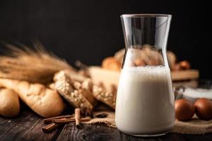 Milch in einer Glasflasche auf einem Holztisch mit Zutaten foto