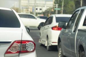 Rückseite des weißen Autofahrens oder Stoppens auf der Asphaltstraße. mit anderen Autos daneben. verschwommen fahren autos durch die vorderkreuzung in die stadt. foto