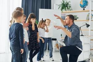 Geschichtenerzähler mit interessanten Informationen. gruppe von kinderschülern im unterricht in der schule mit lehrer foto