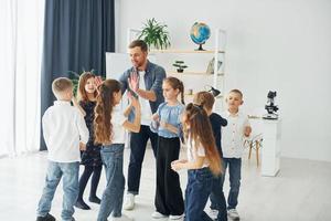 high fives geste. gruppe von kinderschülern im unterricht in der schule mit lehrer foto