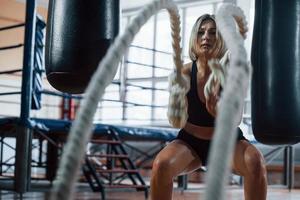 Boxring hinter sich. Blonde Sportlerin trainiert mit Seilen im Fitnessstudio. starkes Weib foto