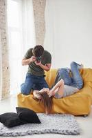 in Freizeitkleidung. fotograf, der ein bild des jungen mädchens macht, das auf dem weißen sofa liegt foto