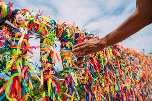 Nahaufnahme von bunten Bändern in Arraial d'Ajuda, Bahia, Brasilien. mannhand, die eine bestellung mit brasilianischen bändern macht foto