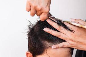 Friseur schneidet einem Jungen die Haare auf weißem Hintergrund, Fokus auf Schere foto