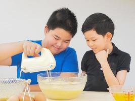 Kinder machen Kuchen mit einer Handmixer-Maschine foto