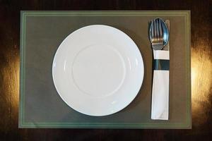 weißer Teller mit Löffelmesser auf einer Matte im Restaurant foto